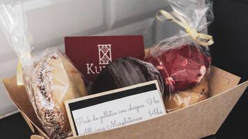 Une boîte cadeau contenant des chocolats et une carte, posée sur une surface sombre, avec une plante en pot en arrière-plan.
