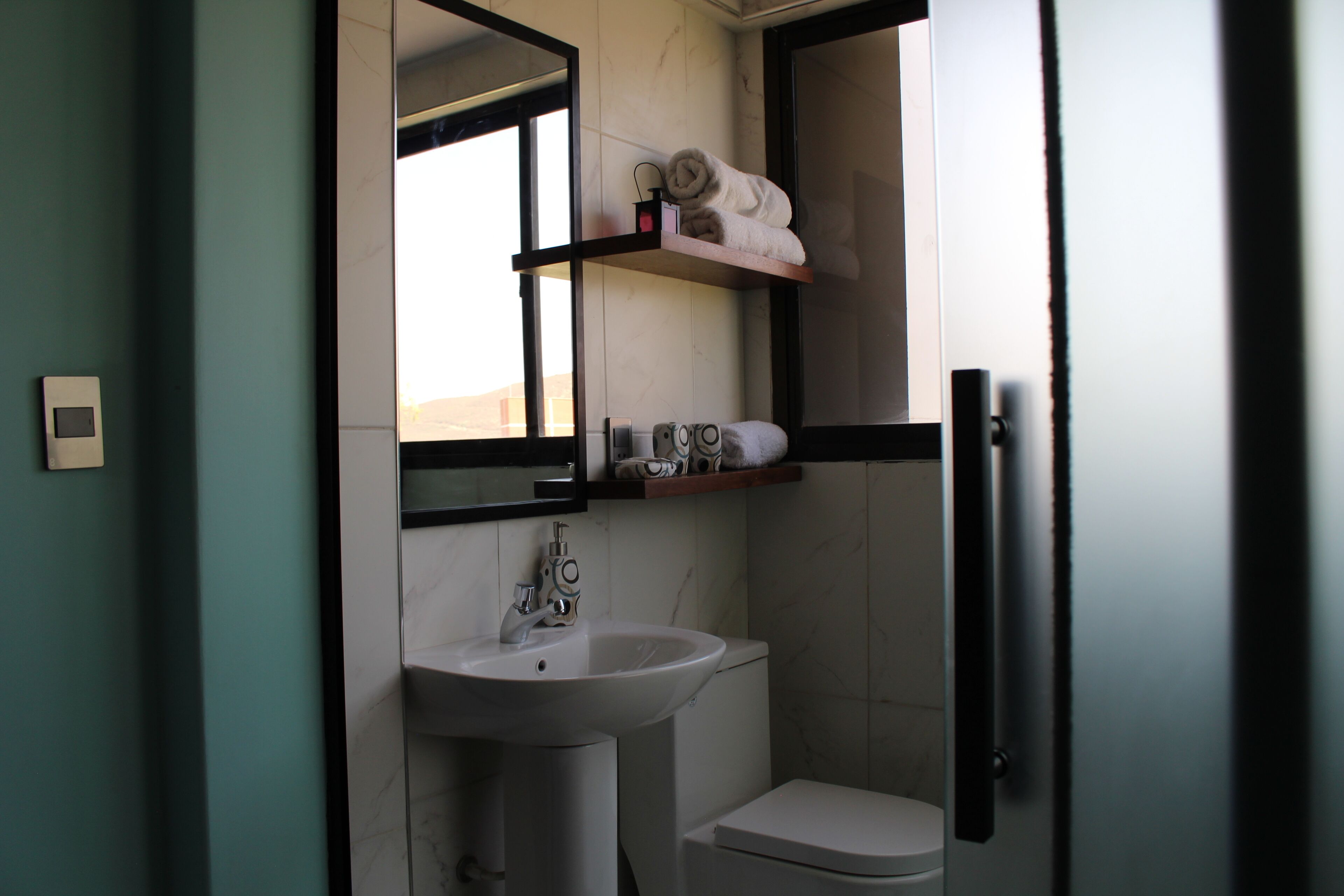 A bathroom with a white sink, a toilet, and a shelf with towels.