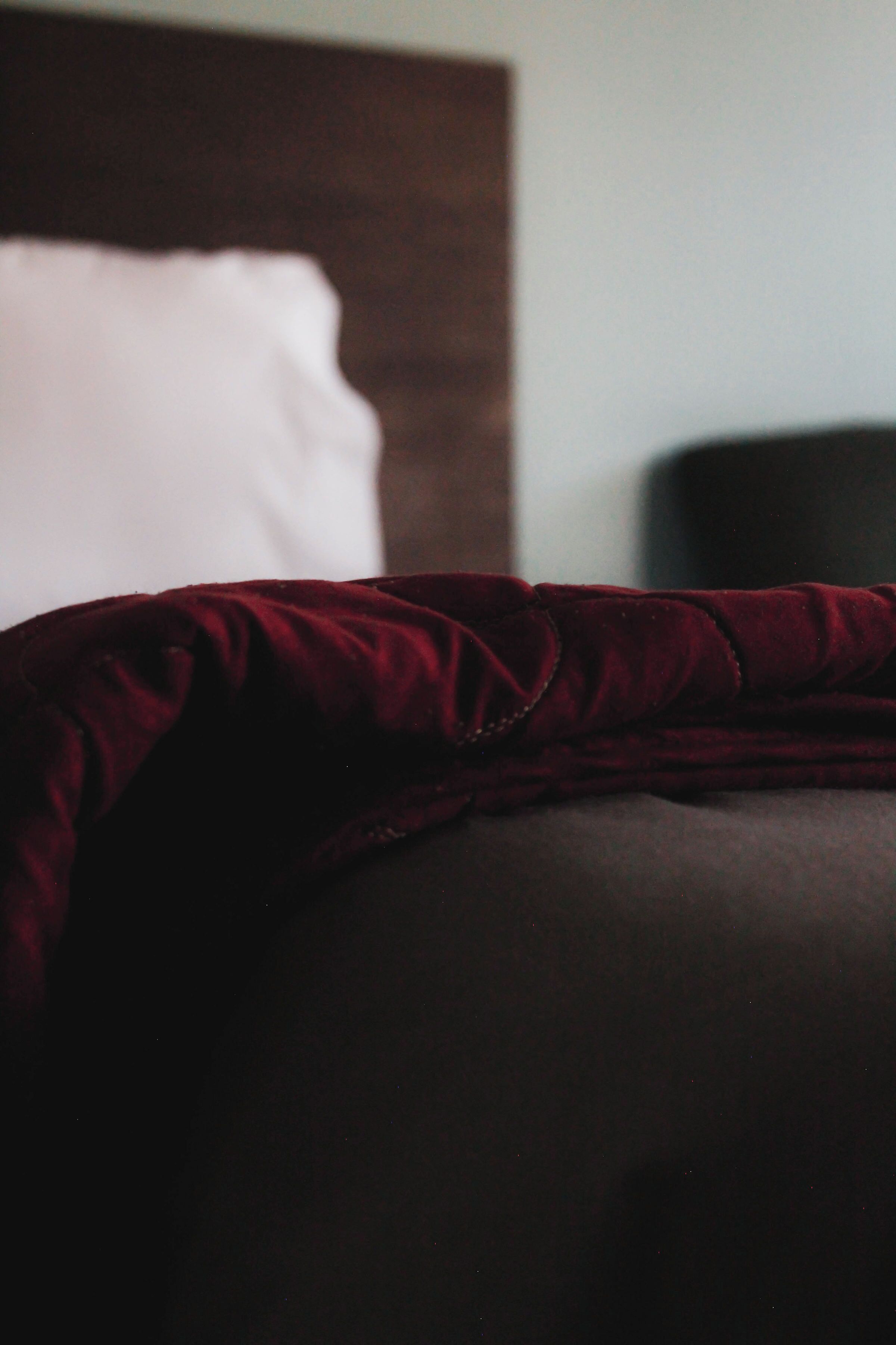 Una cama con cabecera oscura y almohada blanca.