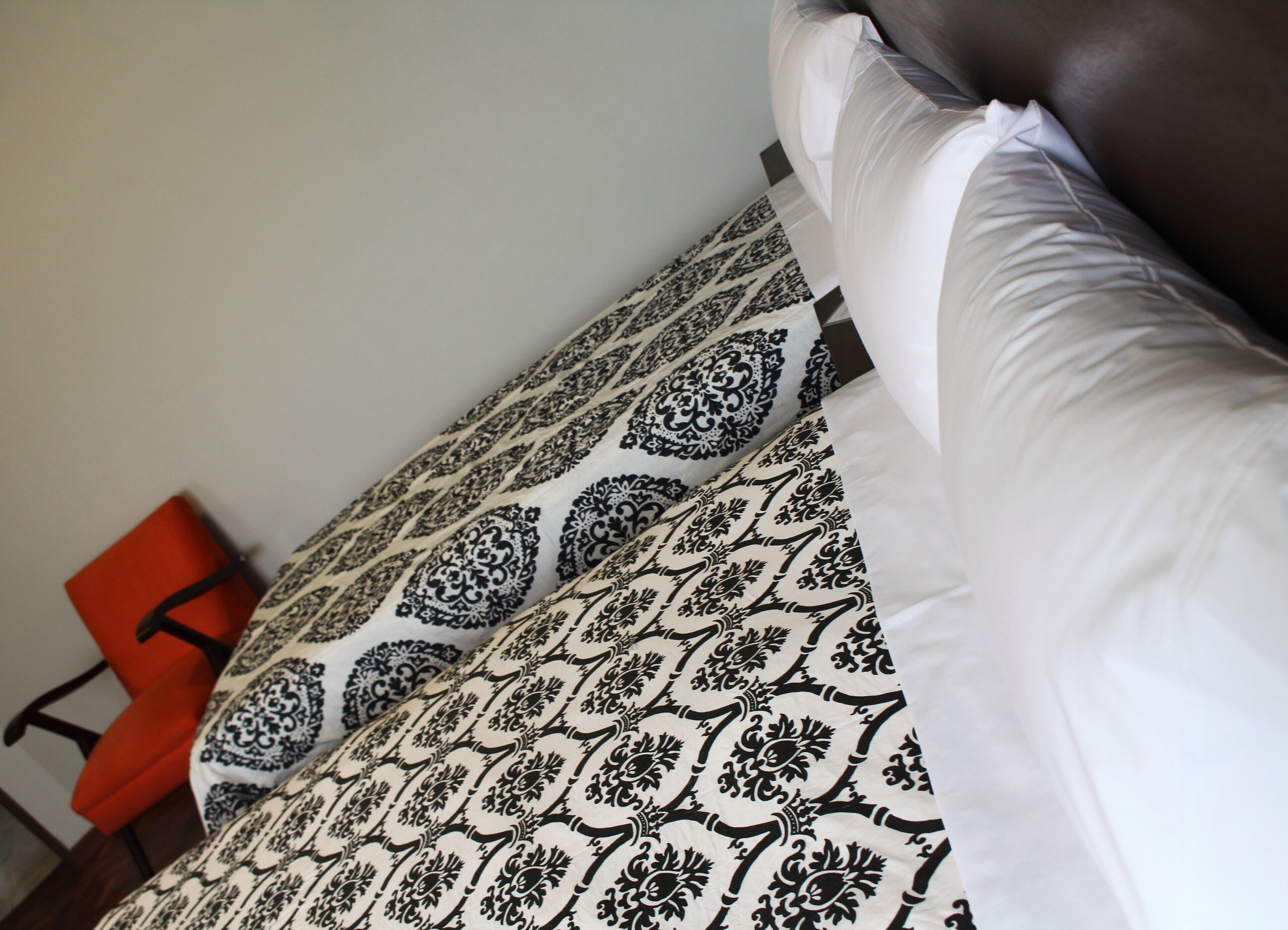 A bed with patterned bedding and a red chair in the background.