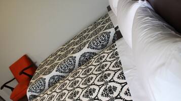 A bed with patterned bedding and a red chair in the background.