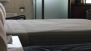 Une chambre d’hôtel comprenant un lit, une table de chevet, une fenêtre et un coin cuisine.