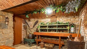 A rustic cellar with stone walls, wooden benches, and shelves filled with wine bottles. - Haus Polivka by Interhome (Hurka u Nemcice)