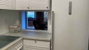 Una cucina con mobili bianchi, un frigorifero Siemens, una finestra con vista su un giardino e un piano cottura.