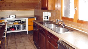 A kitchen with wooden cabinets, a sink, and a window. - Chalet Anthamatten by Interhome (Champery)