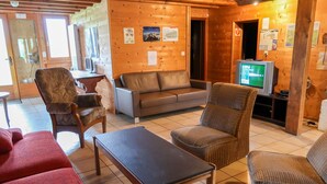 A cozy room with a wooden interior, a sofa, a red couch, and a television. - Chalet Anthamatten by Interhome (Champery)