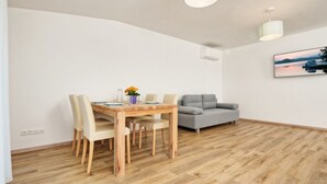 Un coin repas avec une table et des chaises en bois, un canapé gris et un tableau accroché au mur.