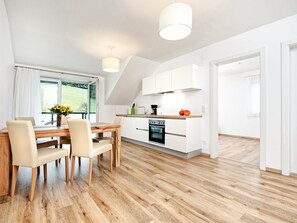 Una cucina moderna con mobili bianchi, un piano di lavoro in legno e un forno integrato.