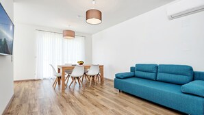 Una sala de estar moderna con un sofá azul, una mesa de comedor de madera y sillas.