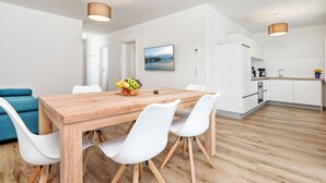Una cocina moderna con armarios blancos, una mesa de comedor de madera y un frutero.