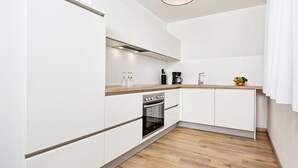 Una cocina moderna con armarios blancos, encimera de madera, horno empotrado y una lámpara colgante.