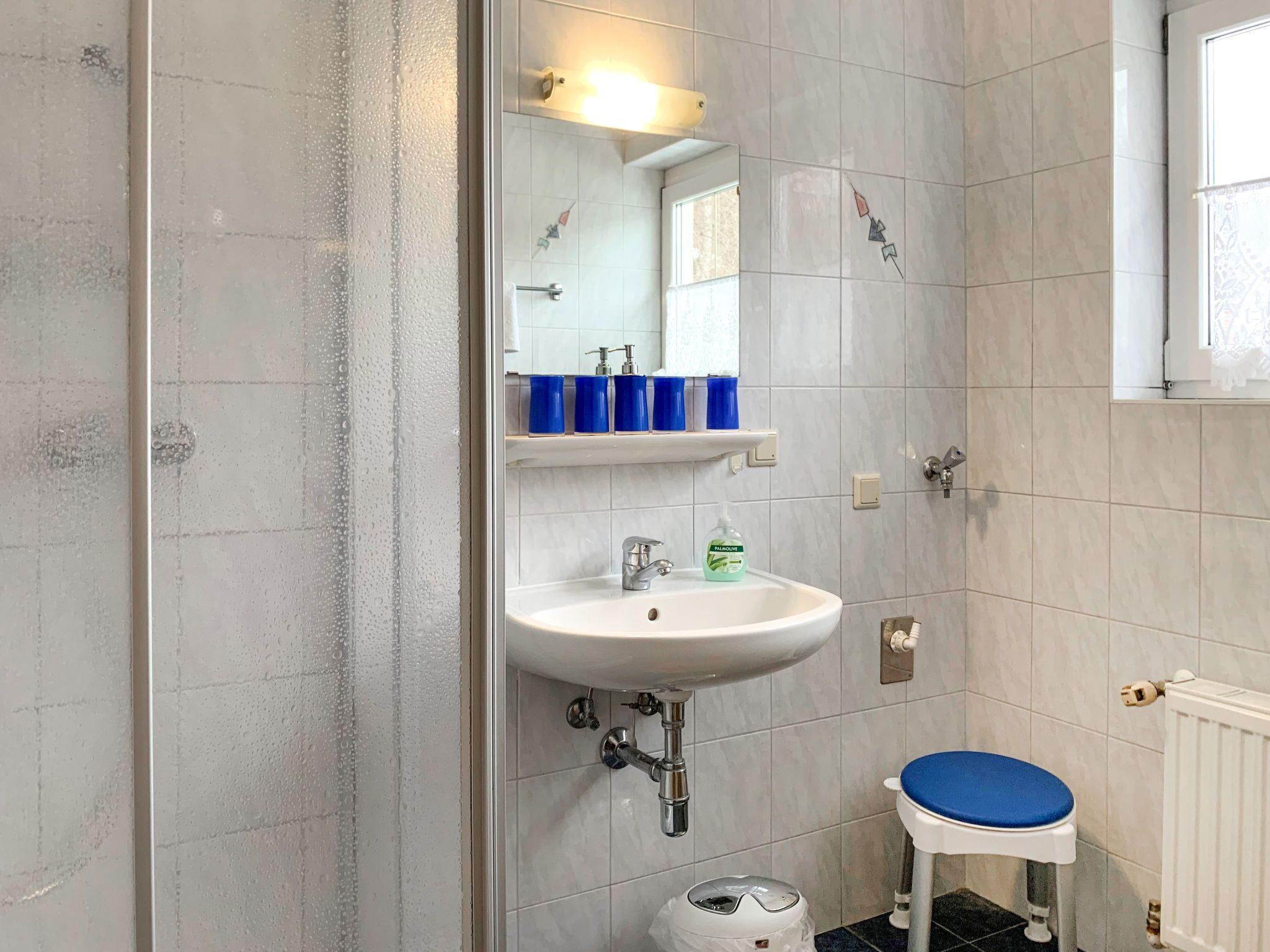 A bathroom with a white sink, a mirror, and a blue toilet.