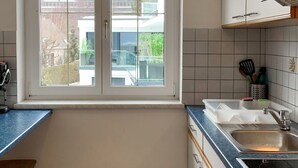 A kitchen with a window, a sink, a stove, and a chair. - Apartment Meran by Interhome (Pörtschach am Wörthersee)