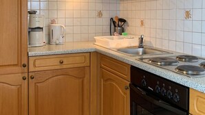 A kitchen with wooden cabinets, a stainless steel sink, a stove, and a microwave. - Apartment Meran by Interhome (Pörtschach am Wörthersee)