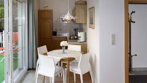 A dining area with a table, chairs, and a vase of flowers. - Apartment Meran by Interhome (Pörtschach am Wörthersee)