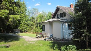 A house with a sloped roof, a chimney, and a small porch with a table and chairs. - Landhaus Grüne Oase by Interhome (Öblarn)