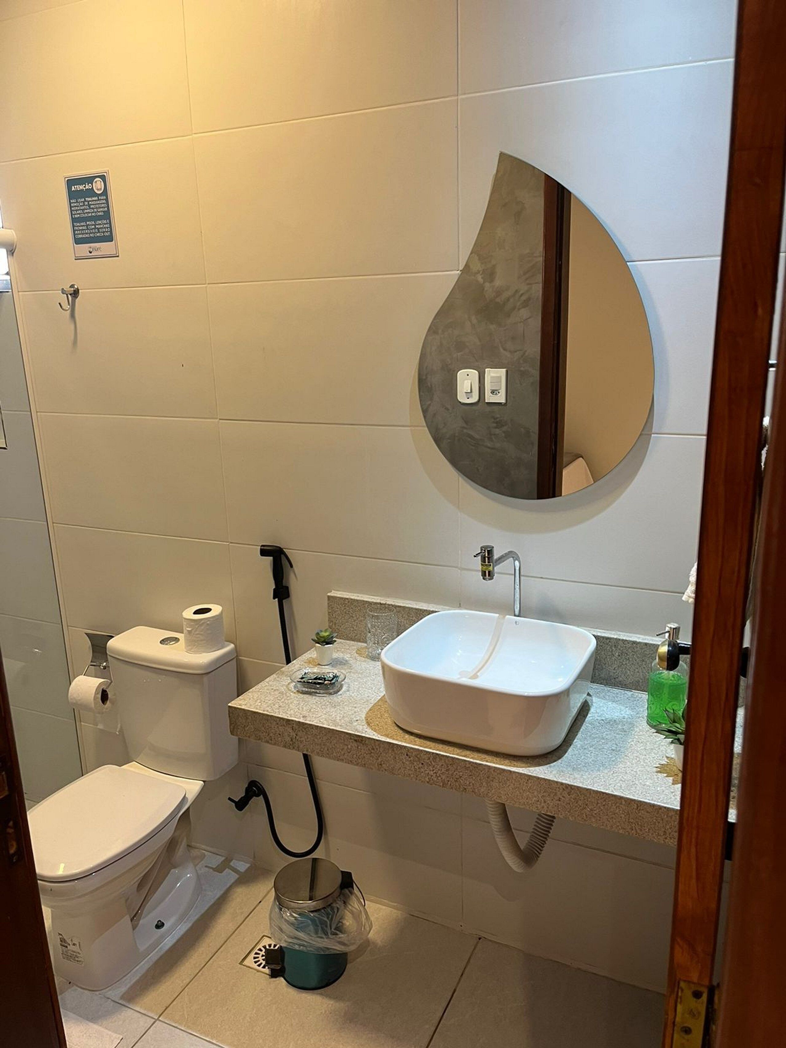 A bathroom with a toilet, sink, and mirror.
