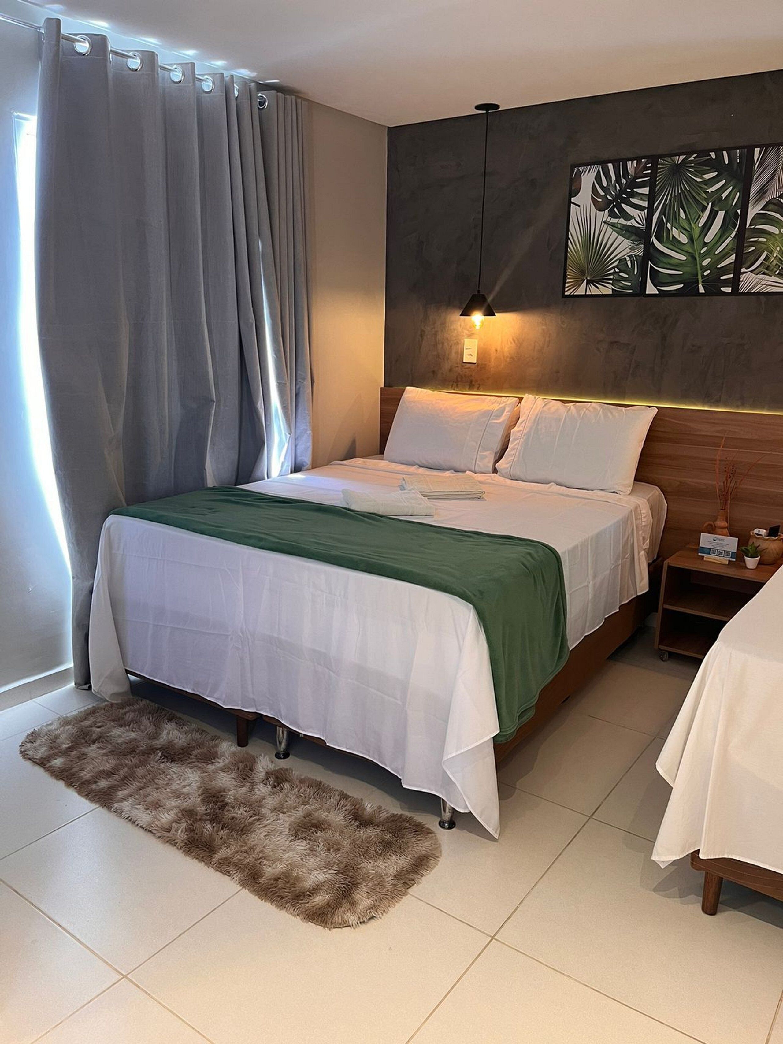 Een moderne slaapkamer met een groot bed, een zacht tapijt, een nachtkastje en een wandlamp.