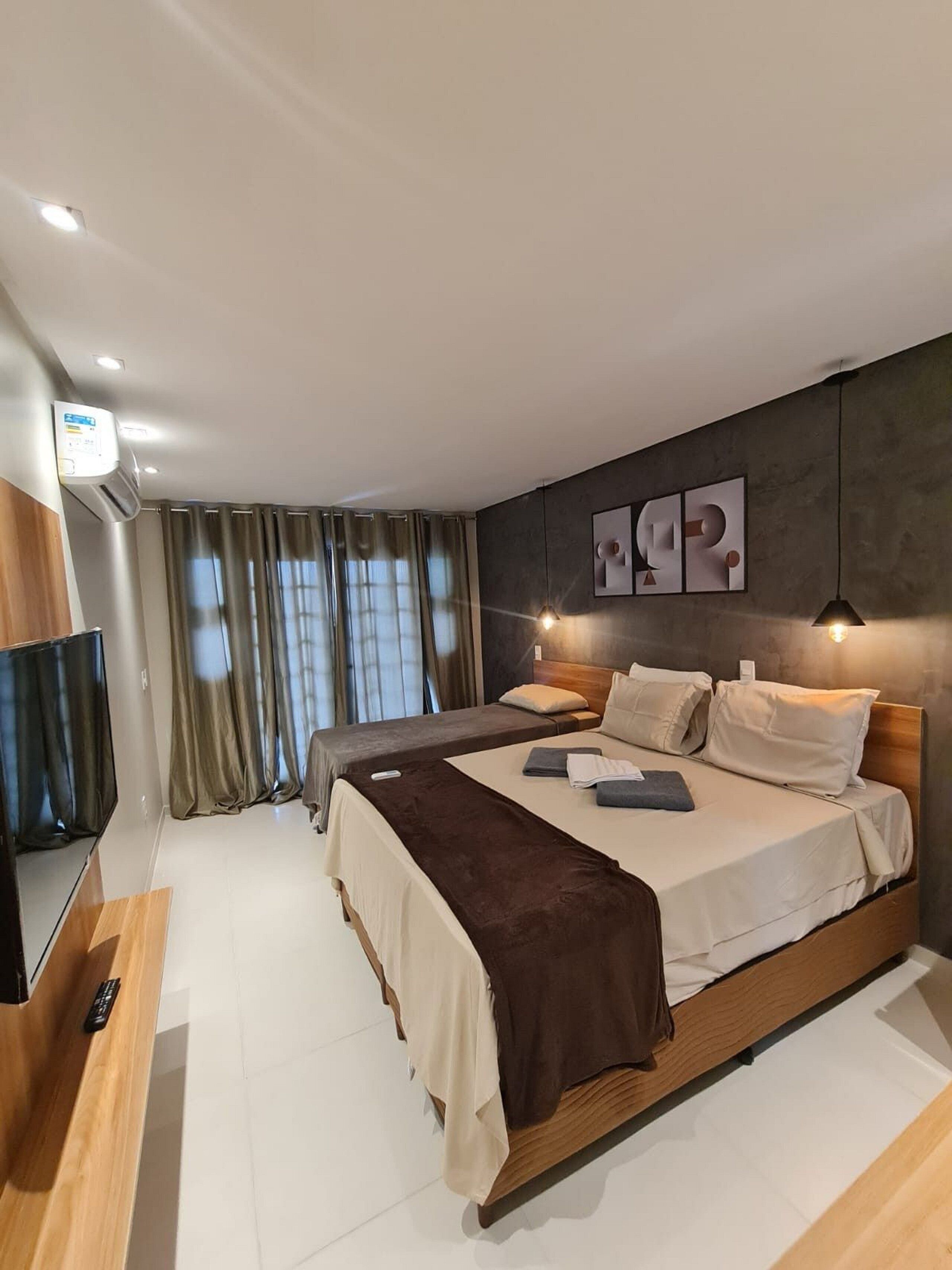 A modern bedroom with a large bed, a TV, and a flat-screen TV mounted on the wall.
