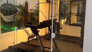 A modern home gym with a treadmill, exercise equipment, and a glass door leading to a patio area. - Maré do Frances (Marechal Deodoro)