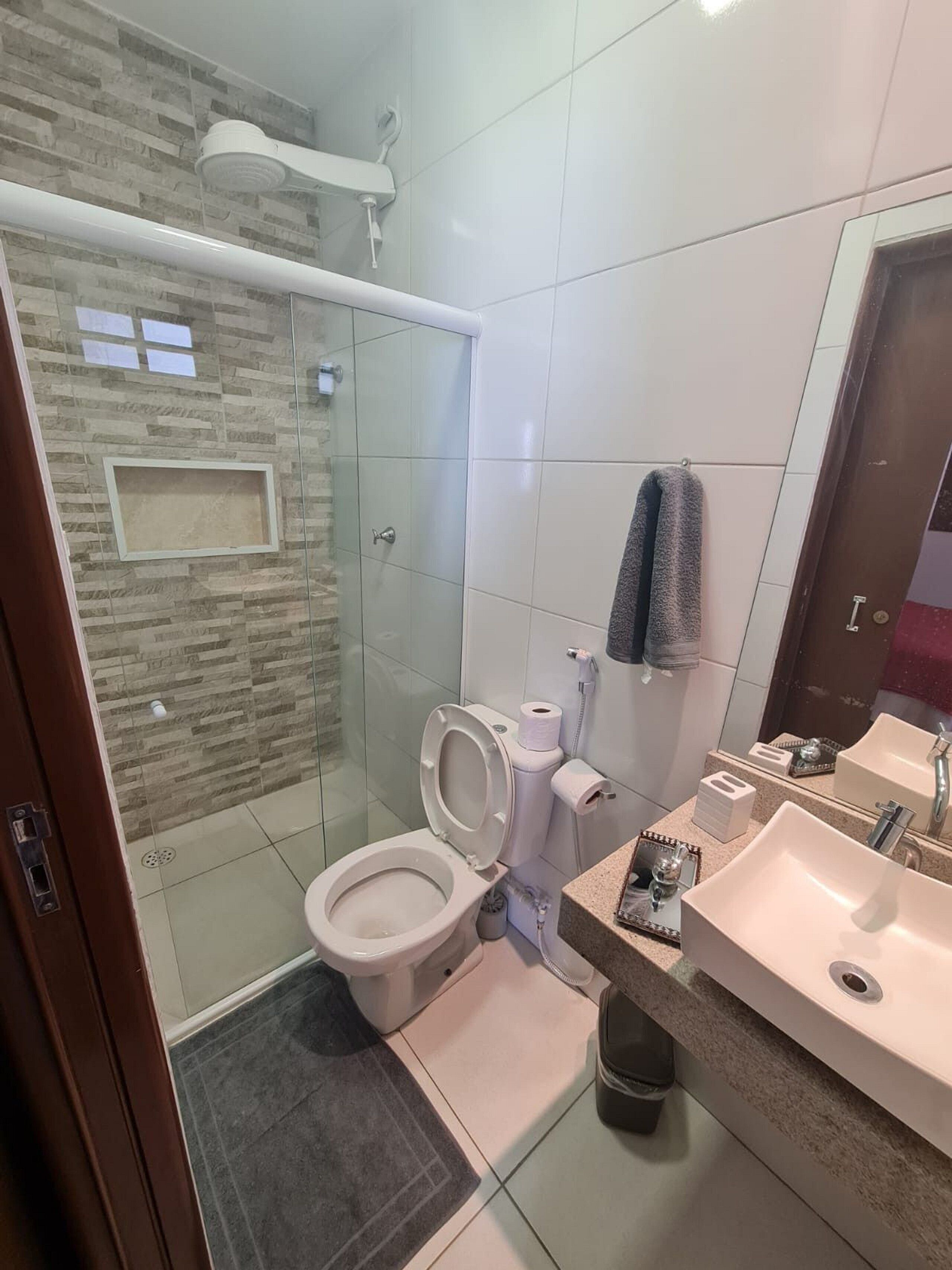 Un baño moderno con ducha de vidrio, inodoro, lavamanos y espejo.