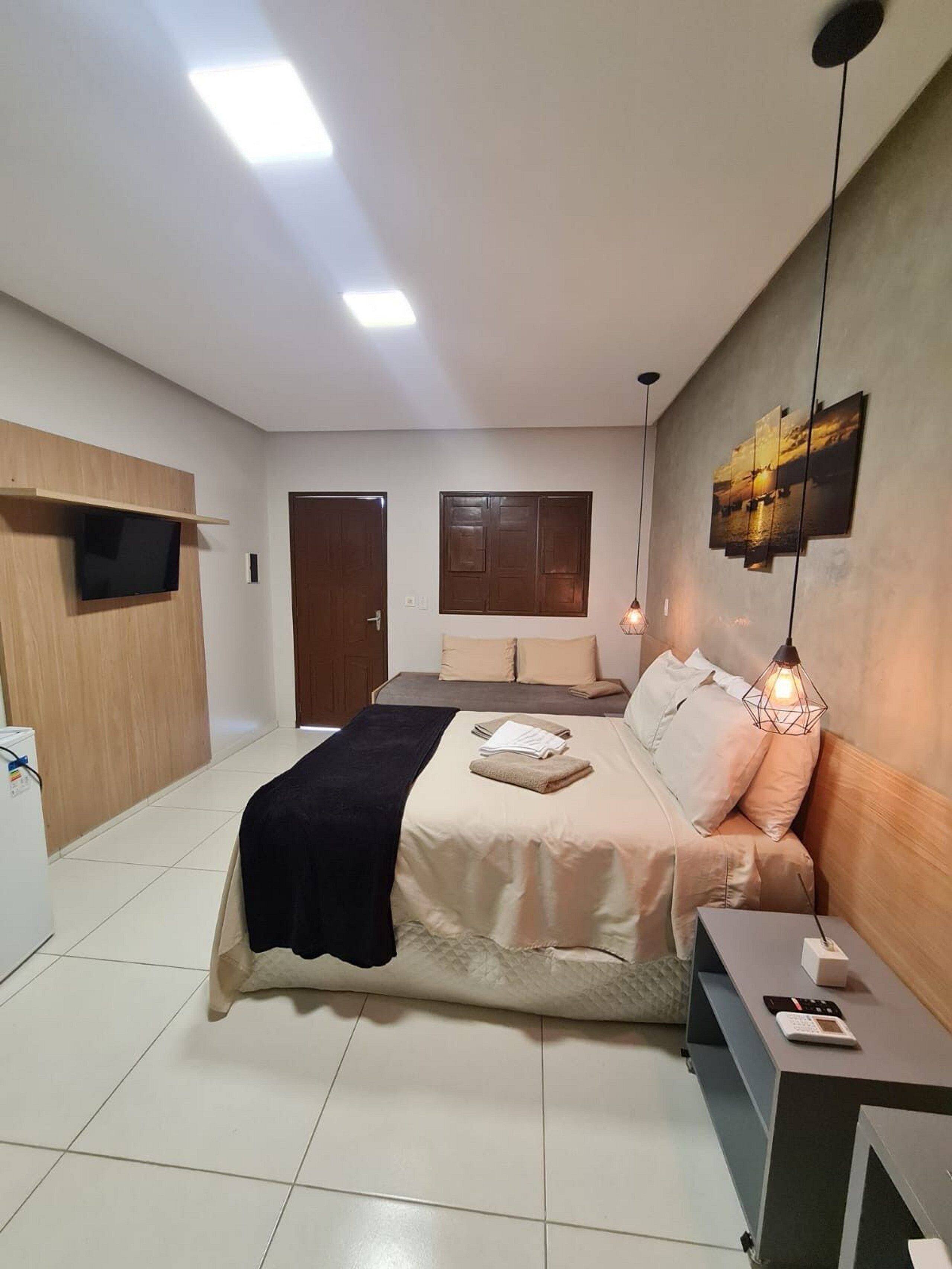 A modern bedroom with a bed, bedside table, and a flat-screen TV mounted on the wall.