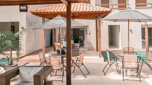 An outdoor patio area with wicker furniture, umbrellas, and a pool. - Maré do Frances (Marechal Deodoro)