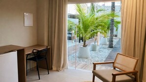 A modern room with a desk, two chairs, a woven rug, and a view of a courtyard with palm trees. - Maré do Frances (Marechal Deodoro)