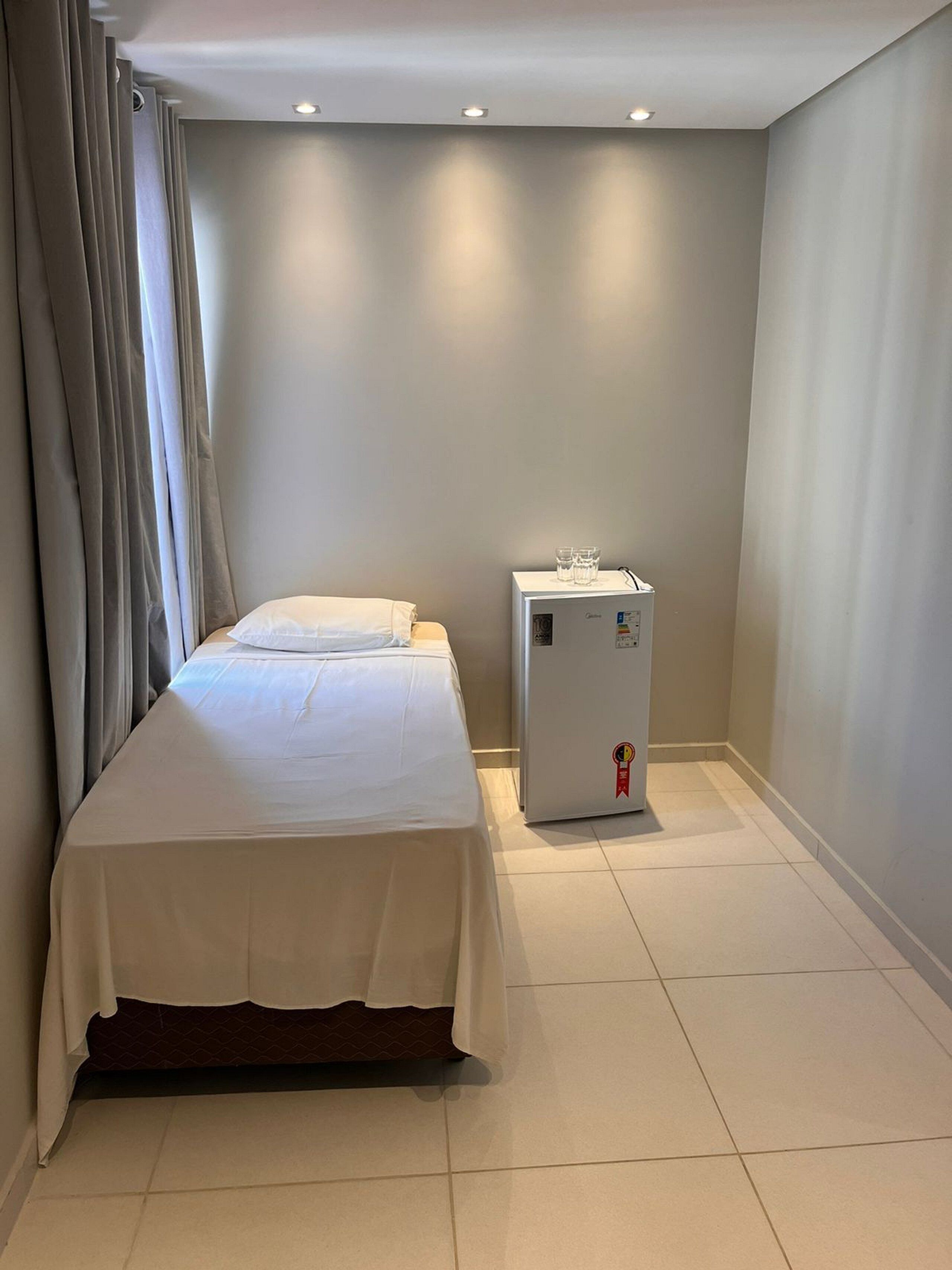 A hotel room with a bed, a minibar, and a small refrigerator.