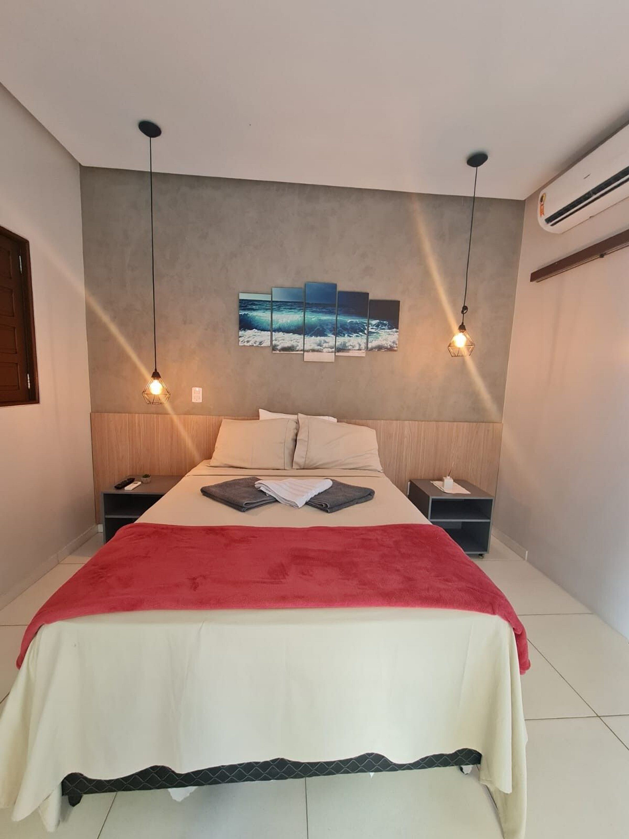 Un dormitorio moderno con una cama, dos mesitas de noche, un edredón rojo y una obra de arte colgada en la pared.