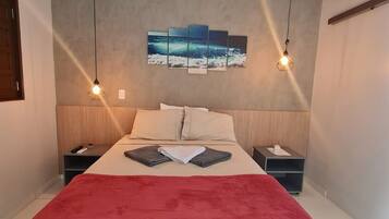 Un dormitorio moderno con una cama, dos mesitas de noche, un edredón rojo y una obra de arte colgada en la pared.