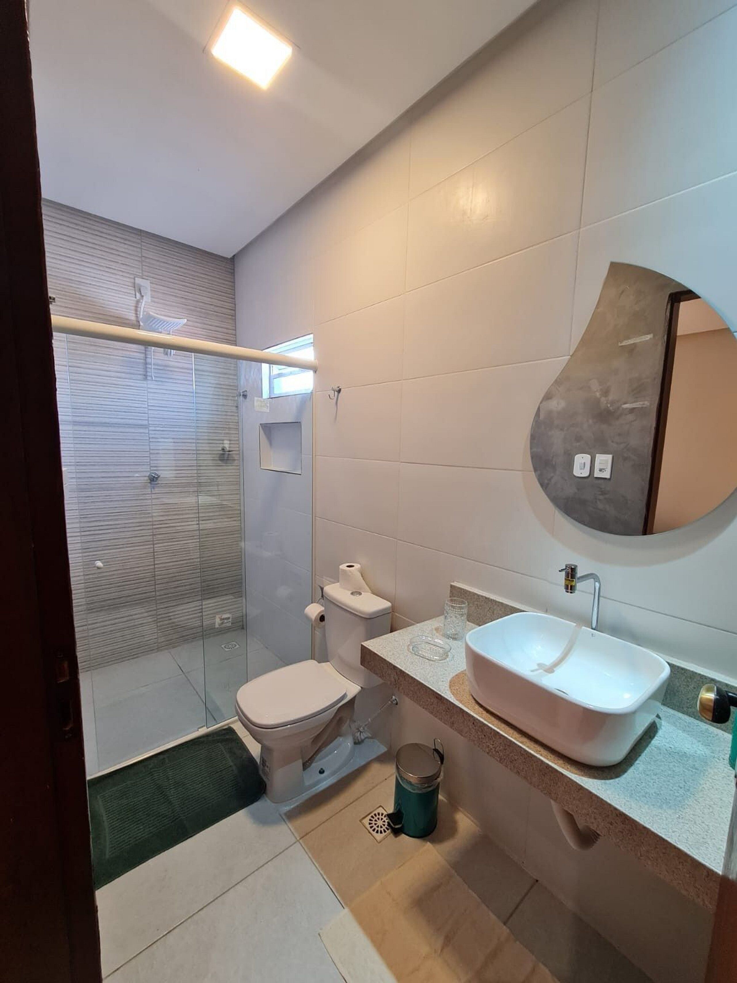 A modern bathroom with a glass shower enclosure, a toilet, a sink with a vanity, and a mirror.