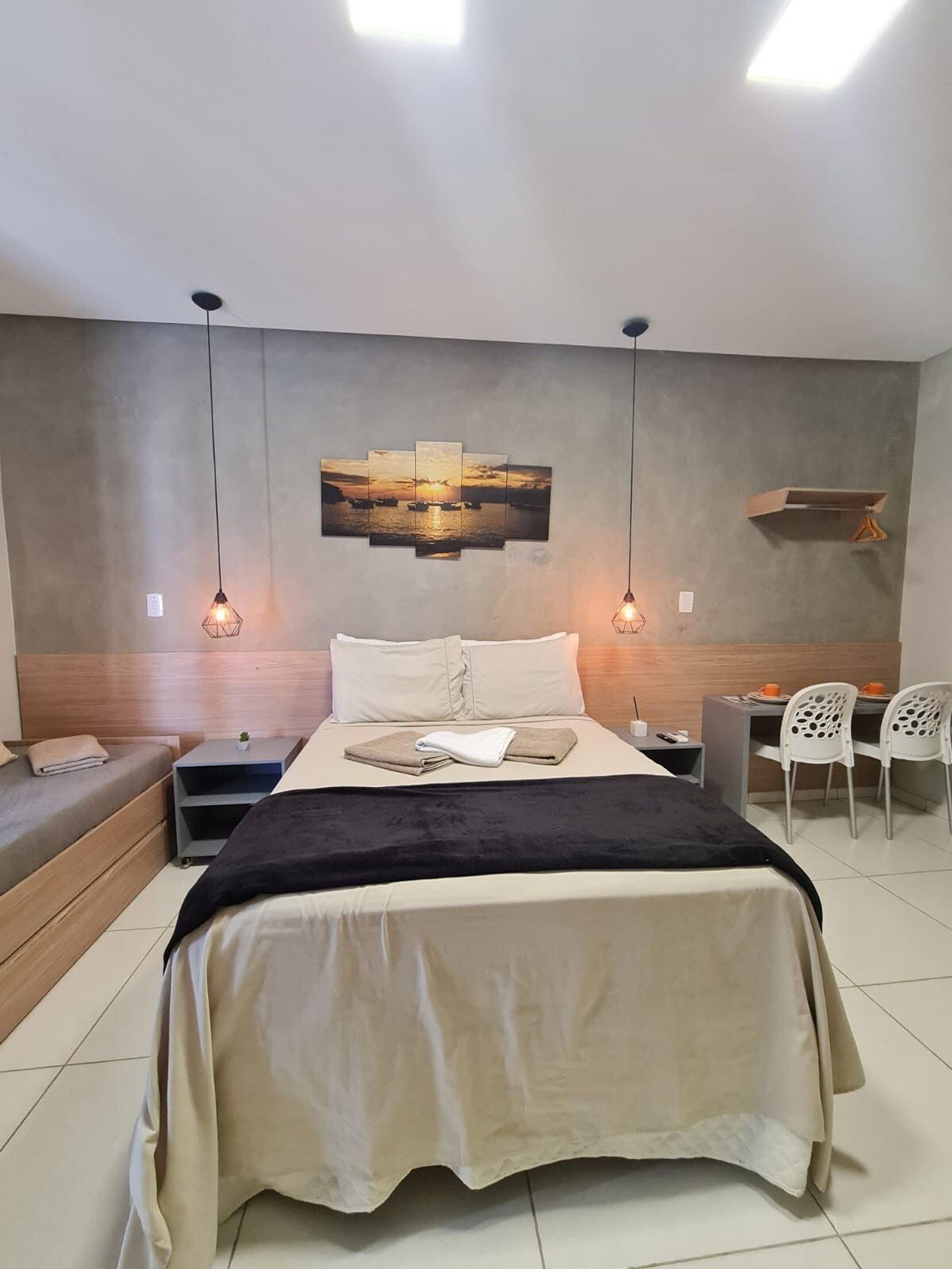 A modern bedroom with a large bed, bedside tables, a desk, and chairs.
