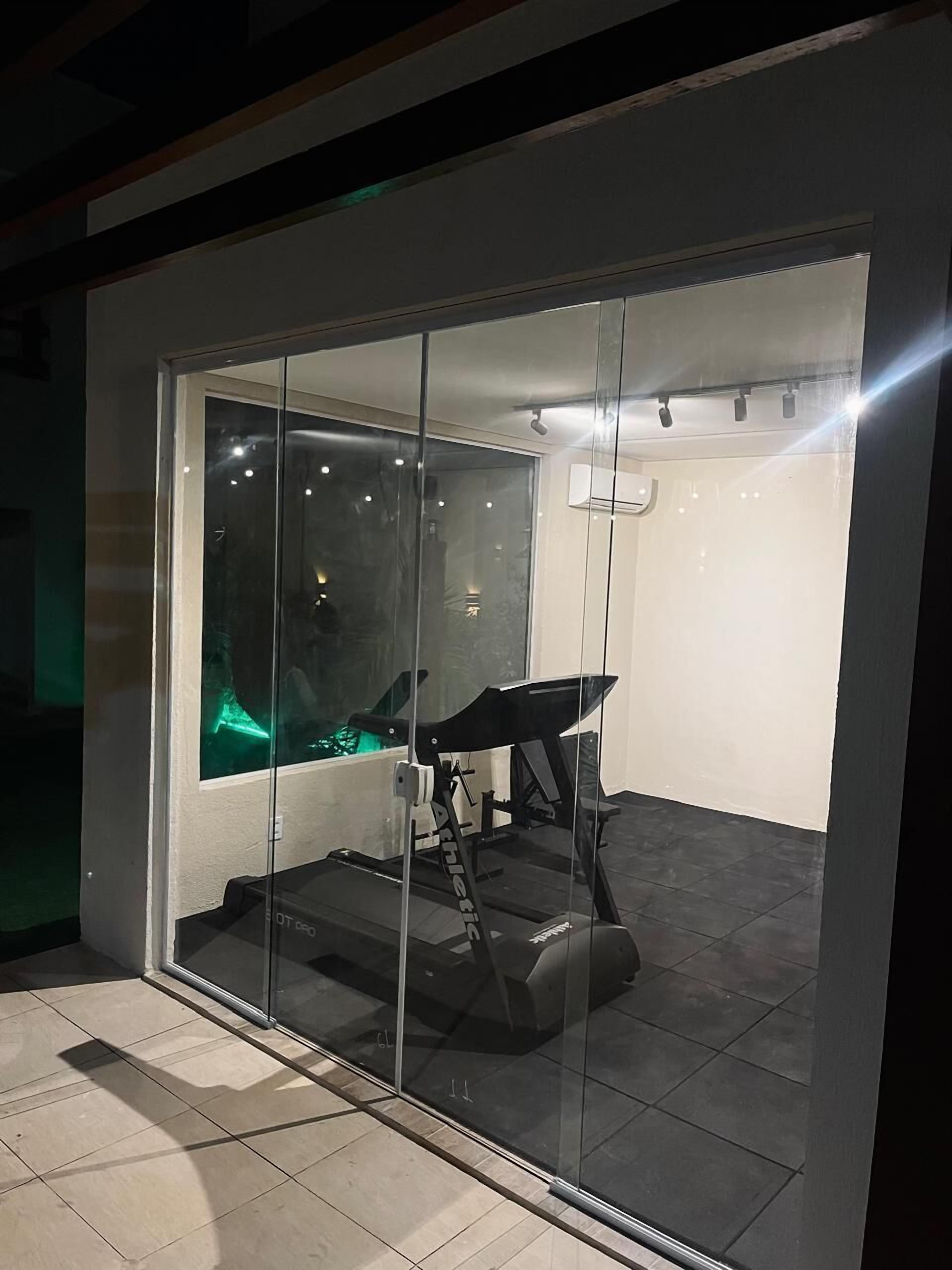A modern room with a treadmill, a glass wall, and a ceiling light fixture.