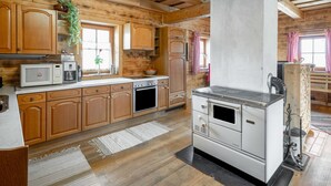 Eine rustikale Küche mit Holzschränken, einem großen Herd und einer Mikrowelle.