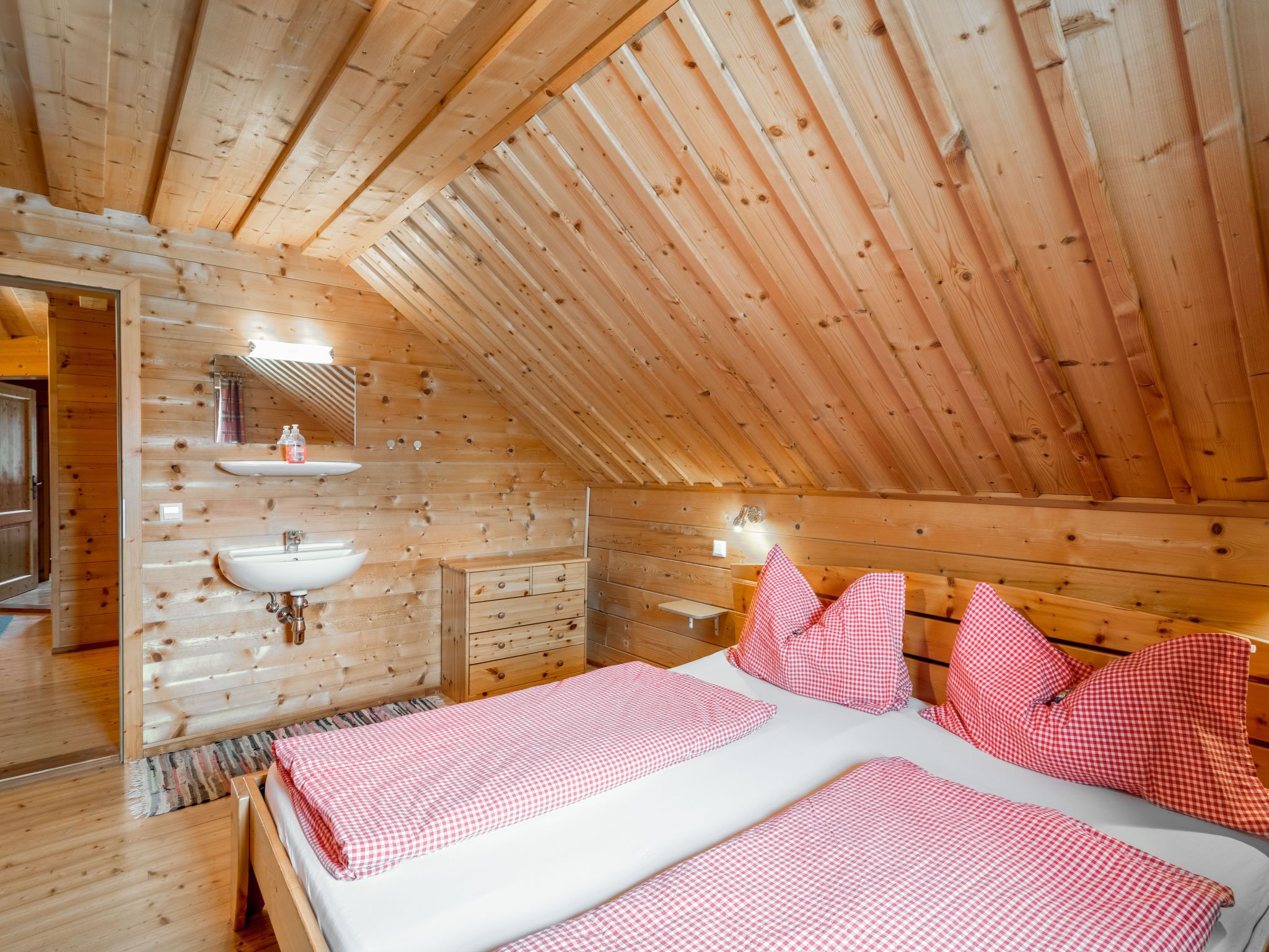 Habitación de cabaña de madera con cama, lavamanos y espejo.
