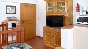 A compact kitchen with wooden cabinets, a television, a microwave, and a small stool. - Apartment Falch by Interhome (Flirsch)