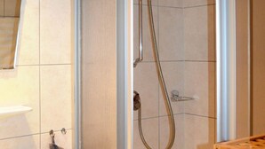 A modern bathroom with a glass-enclosed shower, a white sink, and a wooden shelf with towels. - Apartment Falch by Interhome (Flirsch)
