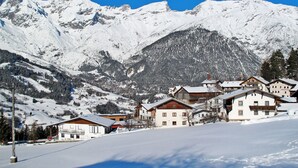 Ein verschneites Bergdorf mit traditionellen Holzhäusern und blauem Himmel.