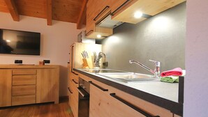 A kitchen with wooden cabinets, a stainless steel sink, and a black countertop. - Piz Munschuns by Interhome (Spiss-Samnaun)
