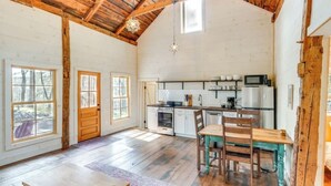 A spacious kitchen with wooden beams, a dining table, and a large window. - Catskills Cabin on 100 Wooded Acres with Lake (Climax)