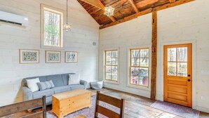 A spacious room with a wooden ceiling, a gray sofa, a wooden chest of drawers, and a wooden bench. - Catskills Cabin on 100 Wooded Acres with Lake (Climax)