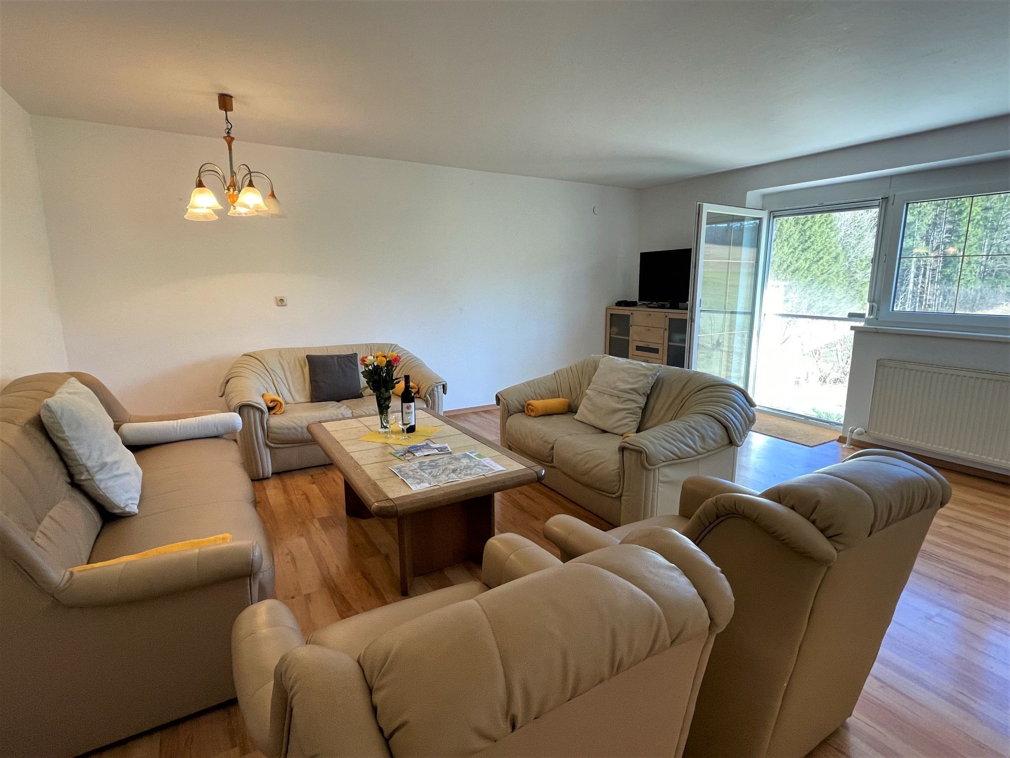 A modern living room with a sofa set, a coffee table with photos, and a TV stand.