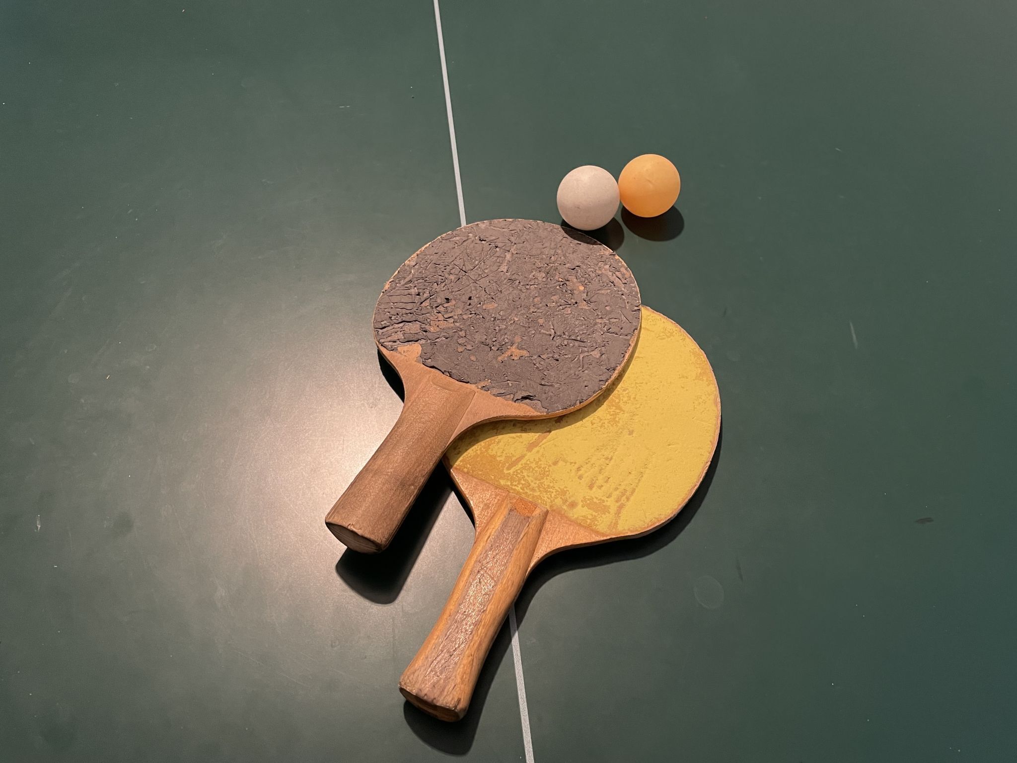 A table tennis table with two paddles and two balls.