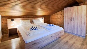 Un dormitorio de cabaña de madera con una cama, dos mesitas de noche y un armario.