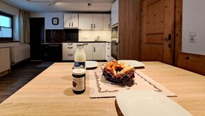Una cocina moderna con armarios blancos, una puerta de madera y una mesa de comedor dispuesta con pan y una botella de leche.
