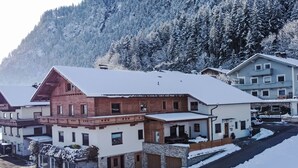 Um edifício coberto de neve com fachada de madeira tradicional, base de pedra e uma extensão moderna.