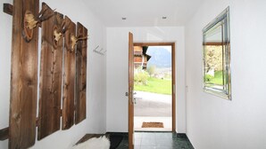 Um corredor com decorações de parede em madeira, um tapete de pele e vista para montanhas e edifícios por uma porta aberta.