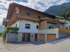 Eine zweistöckige Chalet mit Natursteinfassade, Holzbalkonen und Bergblick.