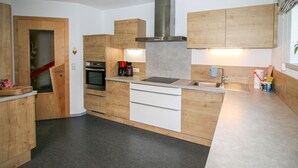 Uma cozinha compacta com armários de madeira, forno embutido, cafeteira e pia de aço inoxidável.